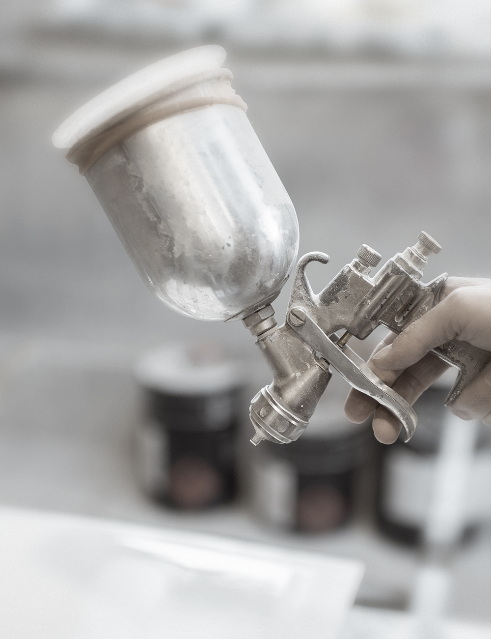 A fabricator's hand holding a vintage spray gun